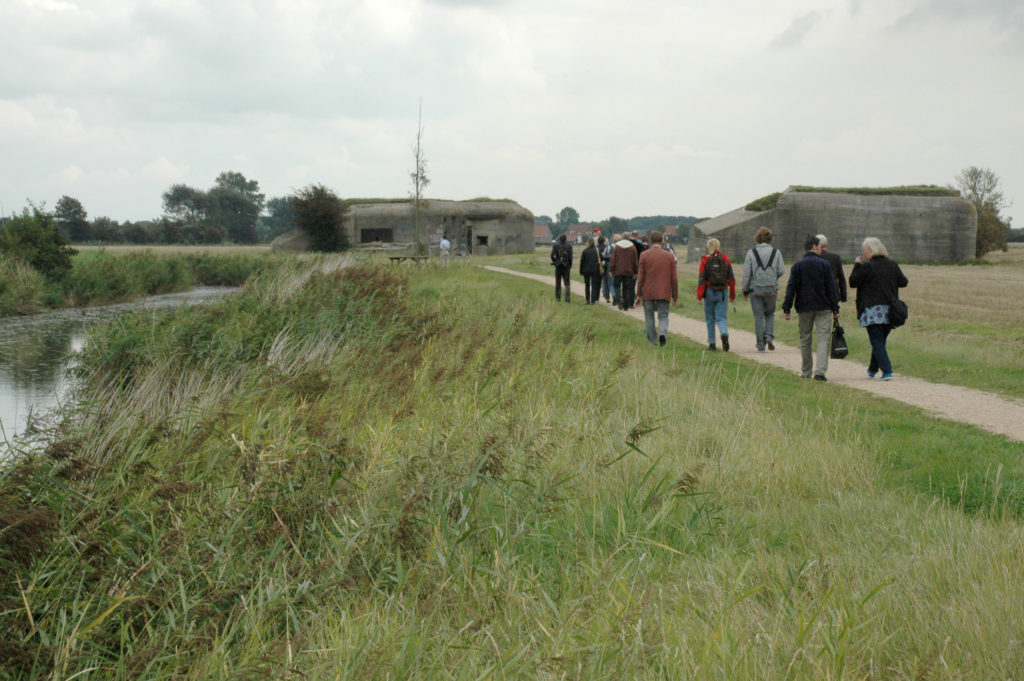 Wandelaars bij linie met bunkers